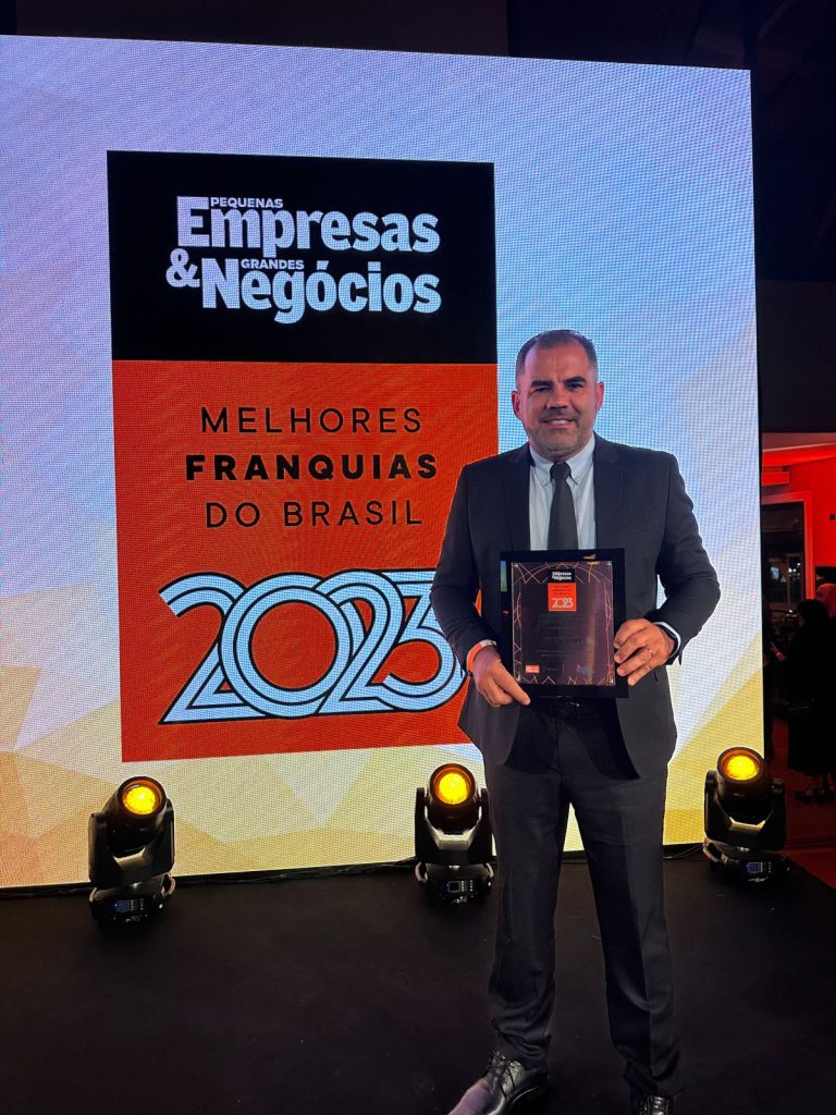 CEO Alex Cavalheiro segurando a placa do prêmio franquia 5 estrelas